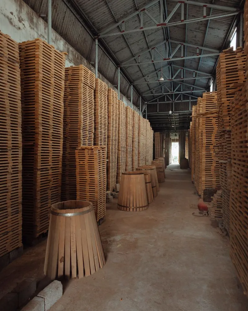 Duelas apiladas para secar en una nave y cascos de madera abiertos en abanico sujetos por un aro.