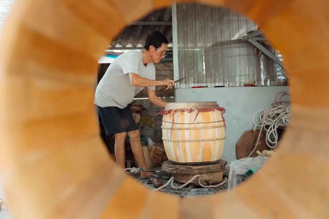 Artesano trabajando sobre un cuerpo de duelas de madera sujeto con aros en un taller.